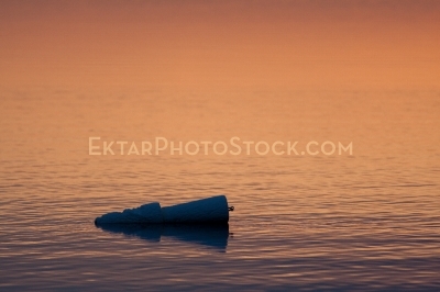 Pink red reflection in the water of sunset with styrofoam floater